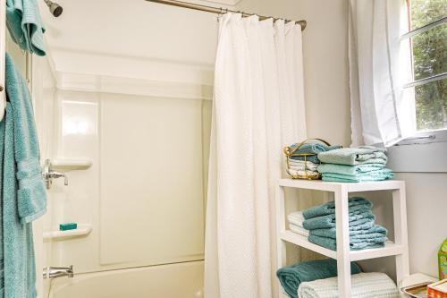La salle de bains est pourvue d'un rideau de douche et d'une étagère avec des serviettes. dans l'établissement Lakeview Vacation Rental - Walk to Crystal Lake!, à Lakeview