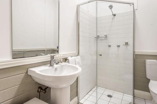 a white bathroom with a sink and a shower at Meroo Meadow Magic Charming Cottage Retreat in Meroo