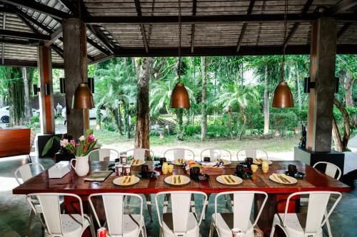 a wooden table with white chairs around it at Tolani Southgate Villa Chiang Mai in Chiang Mai