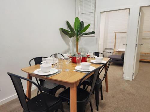 a dining room table with chairs and a plant at U Suites on Webb in Wellington