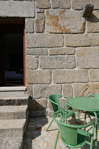 a green table and chairs next to a stone wall at JADS Guesthouse in Fafião