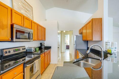 a kitchen with wooden cabinets and a stainless steel sink at 30 Mi to Universal Epic Universe Golf Club Villa in Haines City