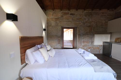 a bedroom with a white bed with a stone wall at JADS Guesthouse in Fafião