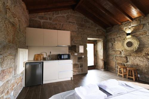 a kitchen in a stone walled room with a bed at JADS Guesthouse in Fafião