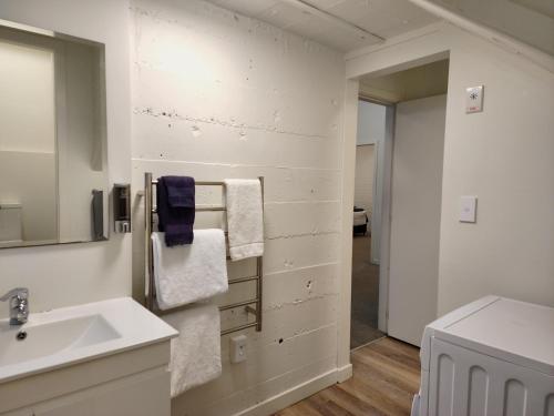 a white bathroom with a sink and a mirror at U Suites on Webb in Wellington