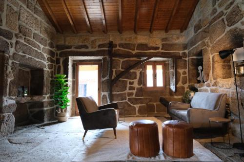 a living room with chairs and a stone wall at JADS Guesthouse in Fafião