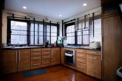 a kitchen with wooden cabinets and windows with a microwave at Tolani Northgate Villa Chiang Mai in Chiang Mai