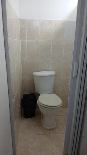 a bathroom with a white toilet in a tiled room at Hostel Recanto in Saquarema