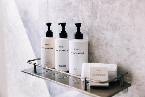 a shelf with three bottles of soap and towels at InterContinental Houston by IHG in Houston