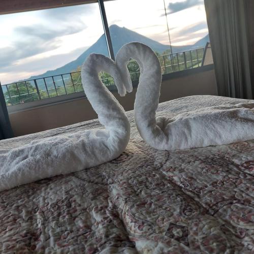 two swans sitting on a bed in front of a window at Villa Esperanza El Castillo in Fortuna