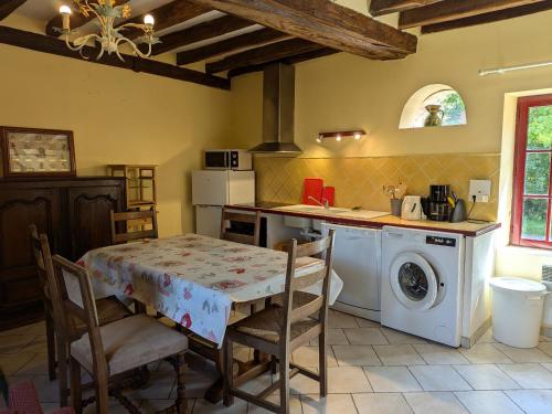 une cuisine avec une table et une machine à laver dans l'établissement Ferme rénovée en Sologne avec cheminée, fibre et jardin, proche de Gien et Sancerre - FR-1-590-81, à Coullons