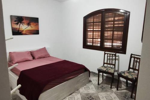 a bedroom with a bed with two chairs and a window at Recanto do Sol em Praia Seca in Araruama