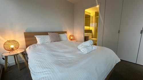 a bedroom with a white bed with towels on it at Nest Apartments on Rose Lane in Melbourne