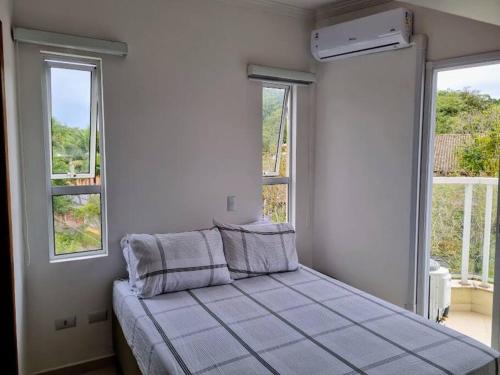 a bed in a room with two windows at Mareazul Ubatuba in Ubatuba