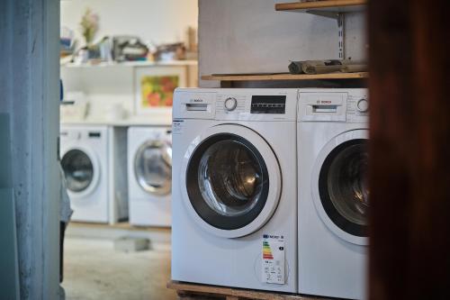 a laundry room with three washing machines in a room at Askegaarden Apartments in Sandved