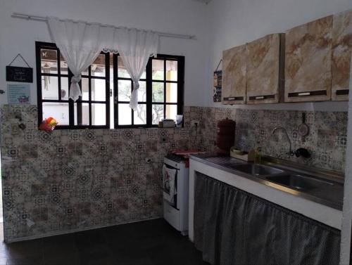 a kitchen with a sink and a stove at Canto Verde casa de veraneio, férias e piscina in Cananéia
