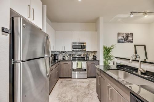 a kitchen with a stainless steel refrigerator and a sink at Tasteful 2BR I Pool I Gym I Parking I Workspace in Dallas