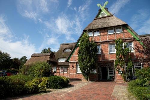 an old brick building with a thatched roof at Cuxlandhotel Studio 204 in Dorum Neufeld