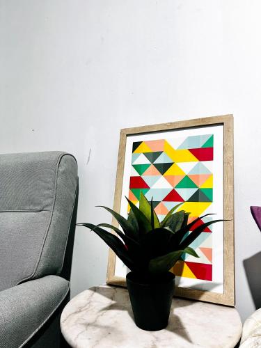 a potted plant sitting on a table next to a painting at 28 OFF Affordable Beautiful Queen Bedroom Near City Swan River Fremantle University in Perth