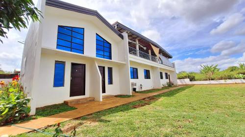 a white house with blue windows and a yard at Concetta Inn in Manolo Fortich