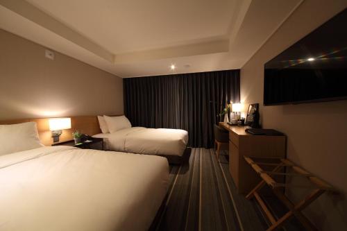 a hotel room with two beds and a desk at Avonhotel Gunsan in Gunsan