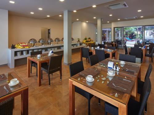 芭達雅南區的住宿－芭提雅瑪瑙精品度假村，餐厅设有木桌、椅子和柜台