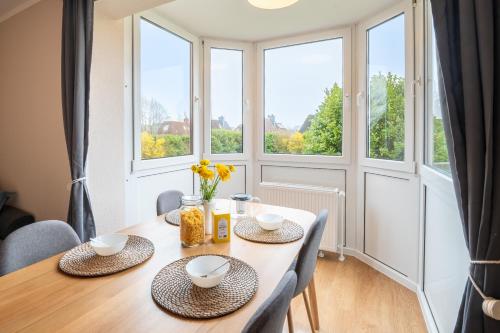 a dining room with a table and chairs and windows at Gemütliche Sonnenwohnung am Meer mit Sauna in Cappel-Neufeld