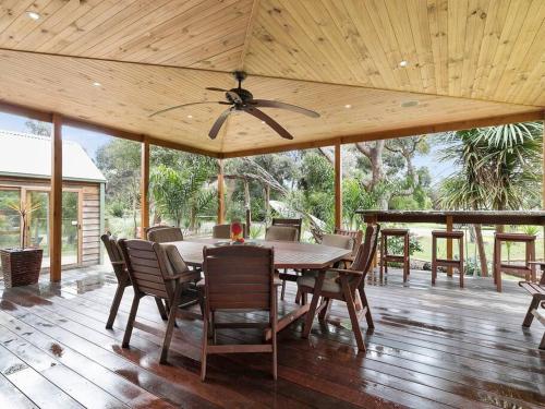 a dining room with a table and chairs on a deck at Silverleaves on the Beach in Rhyll
