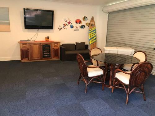 a living room with a table and chairs and a surfboard at Silverleaves on the Beach in Rhyll