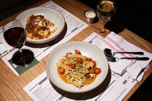 two plates of pasta on a table with wine glasses at Camelia Grove Hotel in Sydney