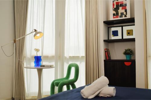 a bedroom with a green chair next to a window at Afiniti 2BR Sunlit Designer - 3 Min To Legoland in Iskandar Puteri