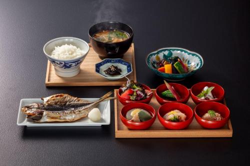 two wooden trays with food and bowls of rice at HOTEL AO Kanazawa in Kanazawa