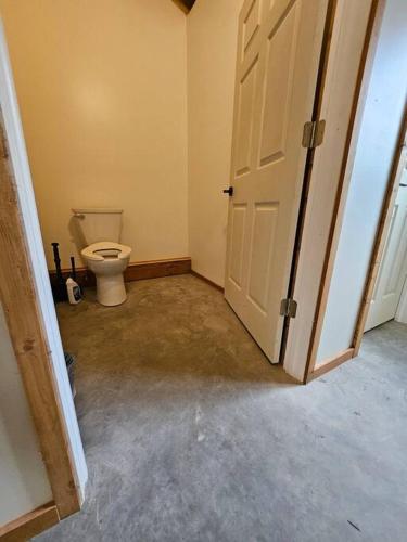 an empty bathroom with a toilet and a door at Sunken Escapes Cabin 8 in New Minas