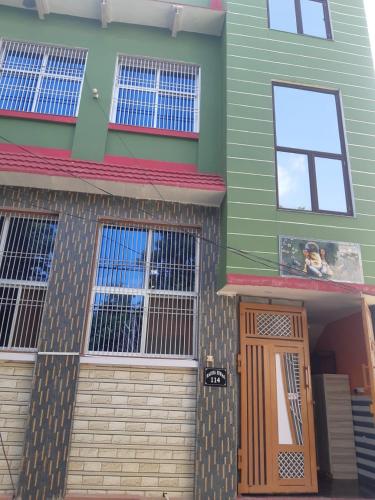 une maison verte avec une porte d'entrée et des fenêtres dans l'établissement RADHA APARTMENTS Stay, à Govardhan