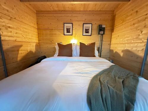 a large white bed in a wooden room at Sunken Escapes Cabin 9 in New Minas