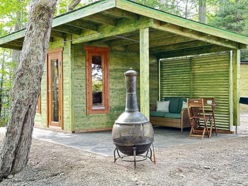 a green house with a grill in front of it at Sunken Escapes Cabin 10 in New Minas