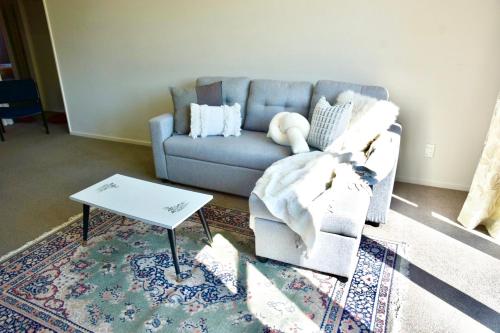 a living room with a couch and a coffee table at Sunny Garden Retreat - 3-BR Home near Mall, City & Airport in Christchurch