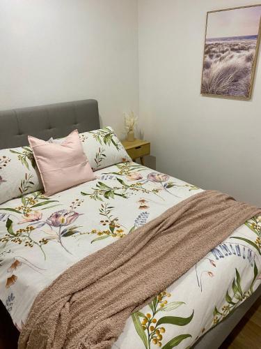a bed with a blanket and a pink pillow at Modern Stylish House in Craigie in Perth