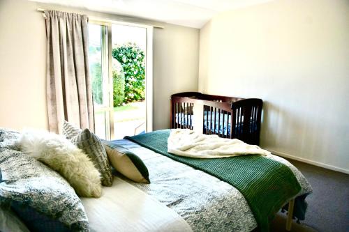 a bedroom with a bed and a window at Sunny Garden Retreat - 3-BR Home near Mall, City & Airport in Christchurch