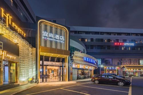 a car parked in a parking lot in front of buildings at Echarm International Hotel Guangzhou South Railway Station Zhongcun Metro Station Branch - Free Shuttle Bus to Canton Fair Complex During Canton Fair Period & Free Deliver Service to Guangzhou Baiyun International Airport in Guangzhou