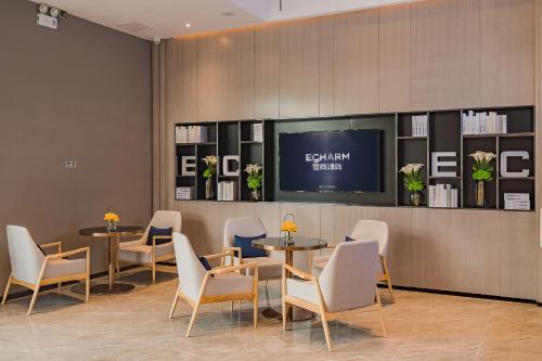 a waiting room with tables and chairs and a flat screen tv at Echarm International Hotel Guangzhou South Railway Station Zhongcun Metro Station Branch - Free Shuttle Bus to Canton Fair Complex During Canton Fair Period & Free Deliver Service to Guangzhou Baiyun International Airport in Guangzhou