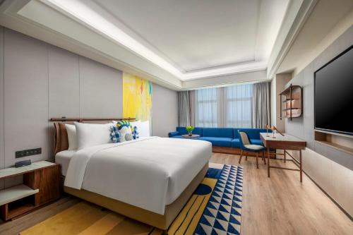 ein Schlafzimmer mit einem großen weißen Bett und einem blauen Sofa in der Unterkunft voco Shanghai Zhangjiang by IHG in Shanghai