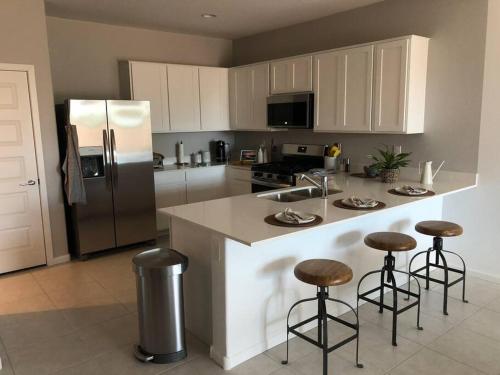 a kitchen with a refrigerator and some bar stools at Cottageza at Harvest in Queen Creek