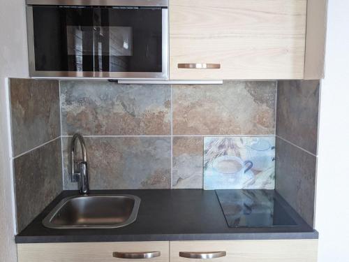 une cuisine avec un évier et un micro-ondes dans l'établissement Studio cosy pour 3 pers avec balcon et équipements de confort aux Adrets-Prapoutel - FR-1-557-130, à Les Adrets