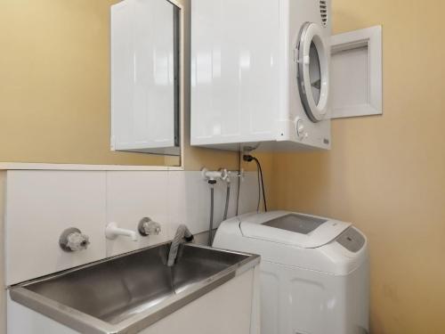 a bathroom with a sink and a washing machine at Cosy Retreat in Nelson Bay in Nelson Bay