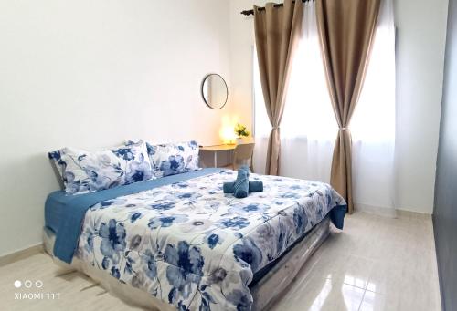 a bedroom with a blue and white bed with a window at Homestay Kuala Terengganu Baroqah Homestay in Kuala Terengganu