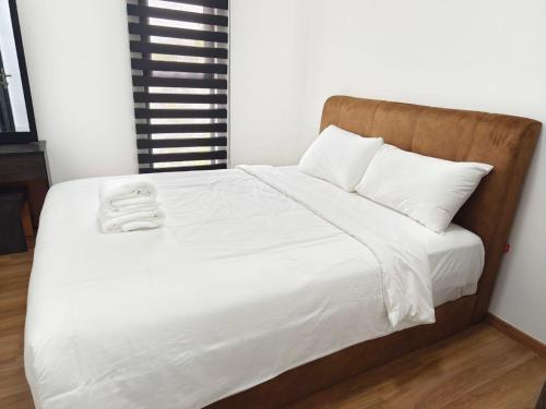 a bed with white sheets and a wooden headboard at The Cove Hillside Ipoh by Glex in Ipoh