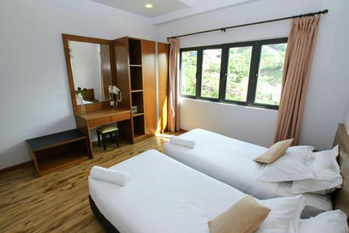 2 bedden in een kamer met een bureau en een spiegel bij The Retreat Mountain & Sunrise view Hilltop Hotel Apartment in Cameron Highlands in Cameron Highlands