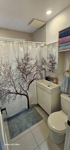 a bathroom with a shower curtain with a tree on it at Spacious bright Apt,Parking and self check-in in Longueuil