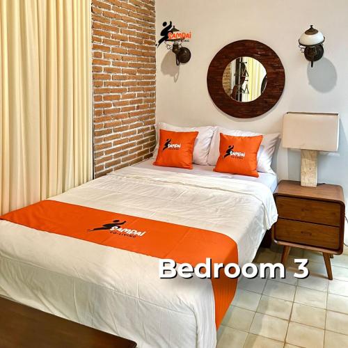 a bedroom with a bed with orange pillows and a mirror at Sampai Villa Amarajota in Kejayan